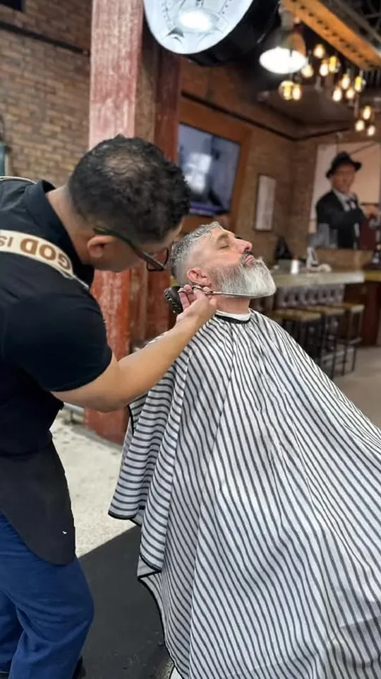 Aldo trimming a client's beard in the chair