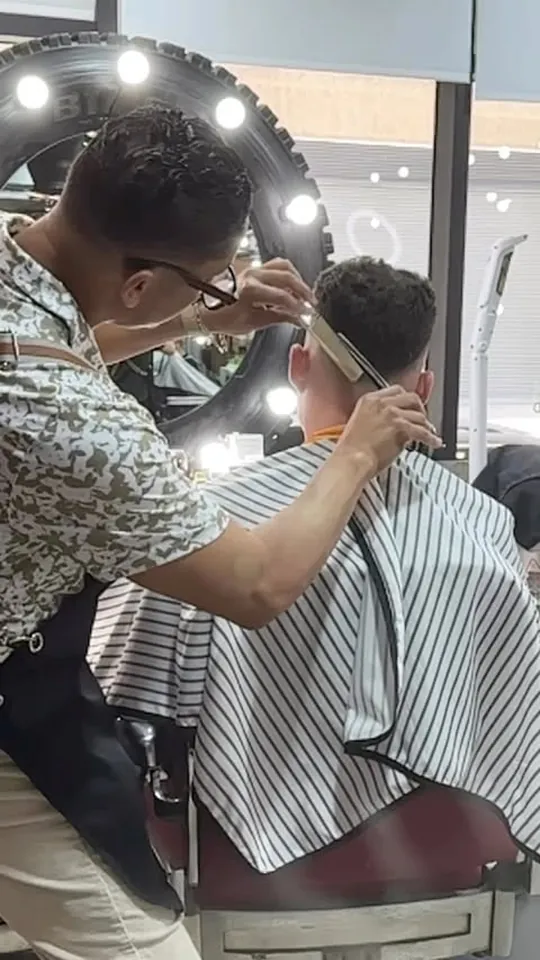 Aldo cutting a client, reflected in the mirror