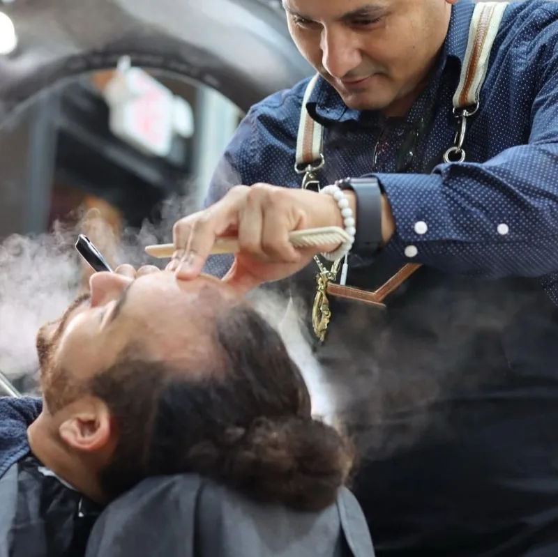 Aldo steaming a client's beard before taking a razor to it
