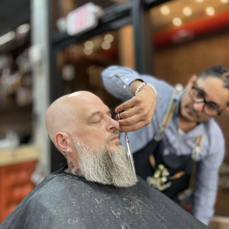 A white beard being shaped with shears in the chair
